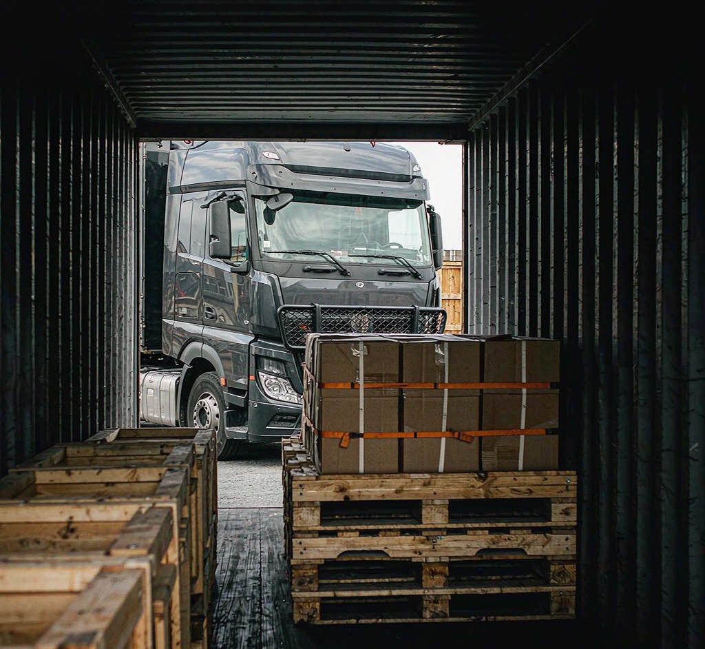 Wooden crates and palletized cargo being loaded into a shipping container